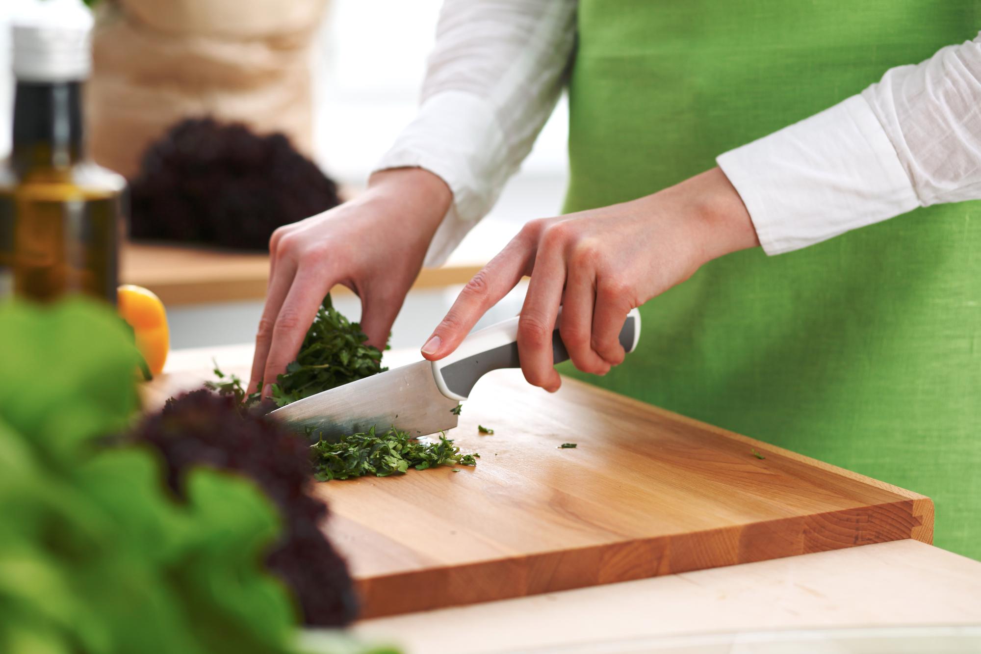 Chef slicing fresh herbs in bright kitchen